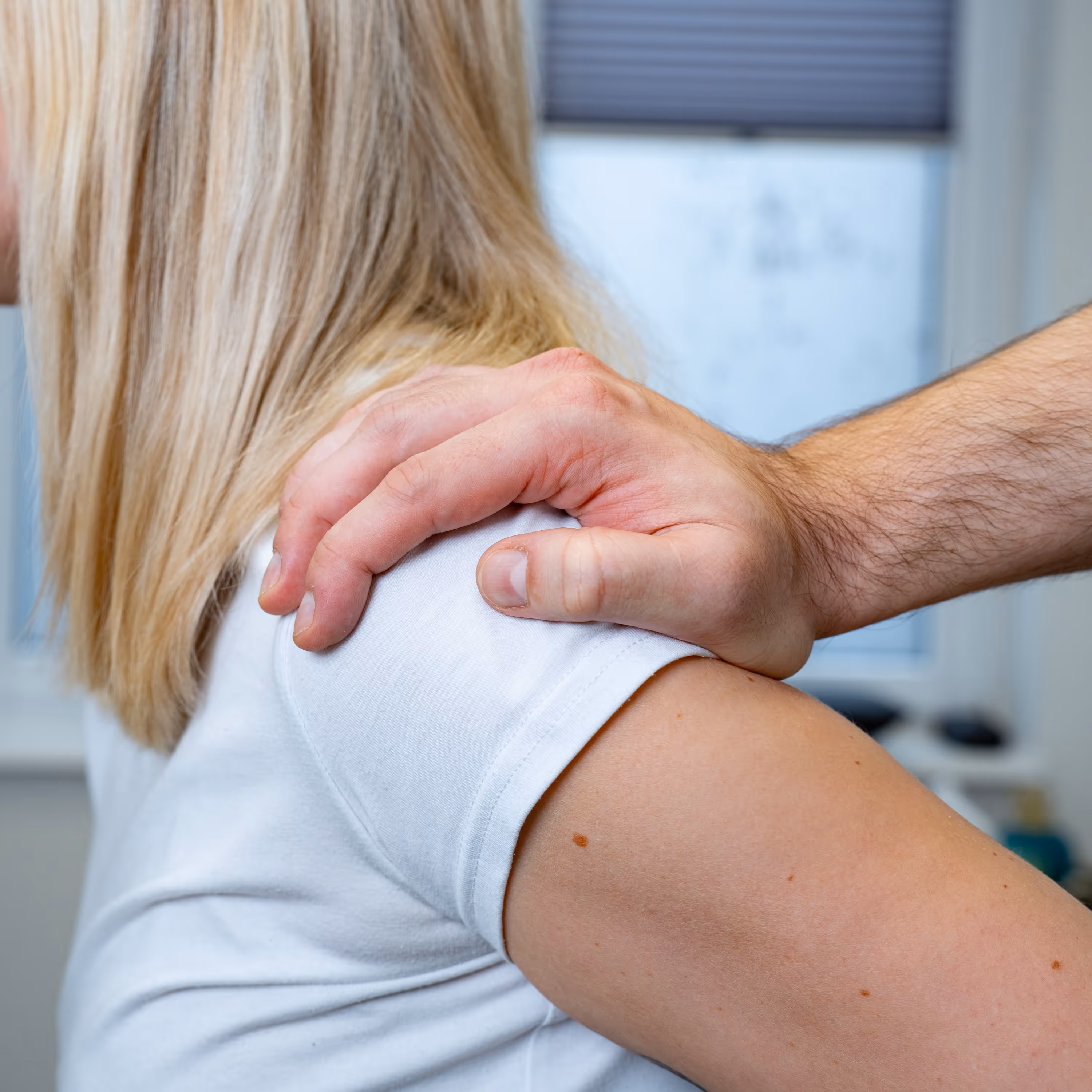 Manuelle Therapie bei FC Physio: Physiotherapeut behandelt die Schulter einer Patientin